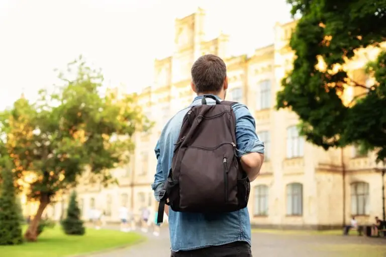 Student at a university walking toward a building with a backpack on his back.
